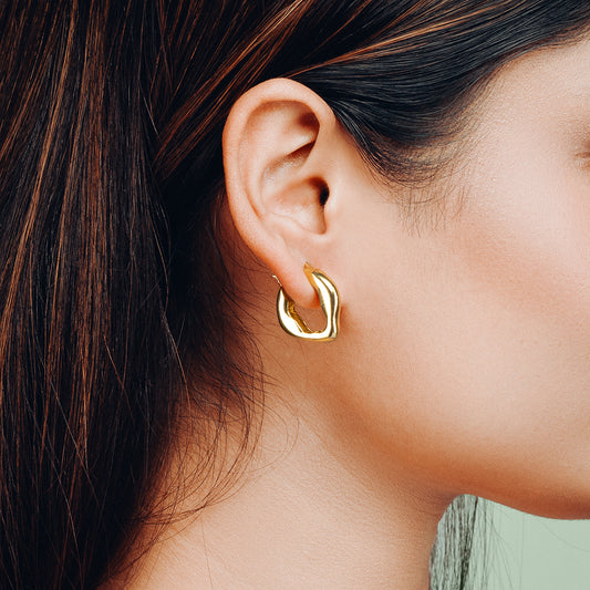 Close-up of a woman wearing Dazzle Hoop Golden Earring by Gulban, a bold demi fine jewellery piece in 18k gold plated finish designed for a modern statement look.