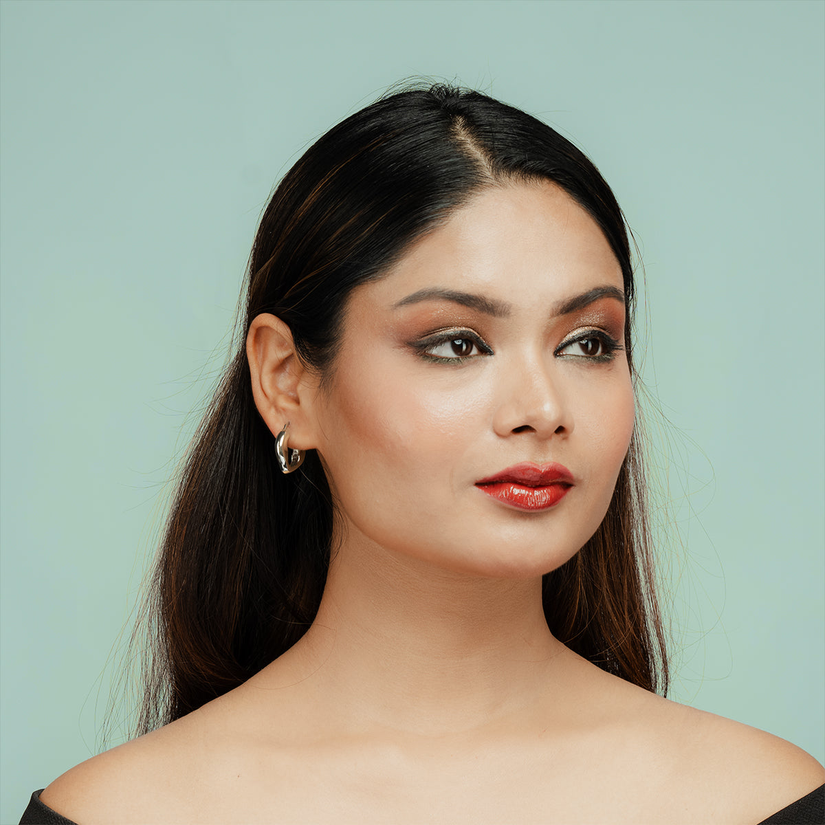 Model wearing Gulban’s Dazzle Hoop silver finish earring styled with evening makeup, a minimalist 18k gold plated demi fine jewellery essential offering everyday sophistication and comfort fit