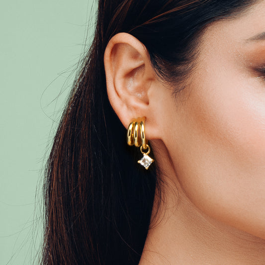 Close-up view of Gulban's Hyperbola Gold Hoop Earring in demi fine jewellery finish, 18K gold plated with a sparkling solitaire charm, designed for elegant modern women.
