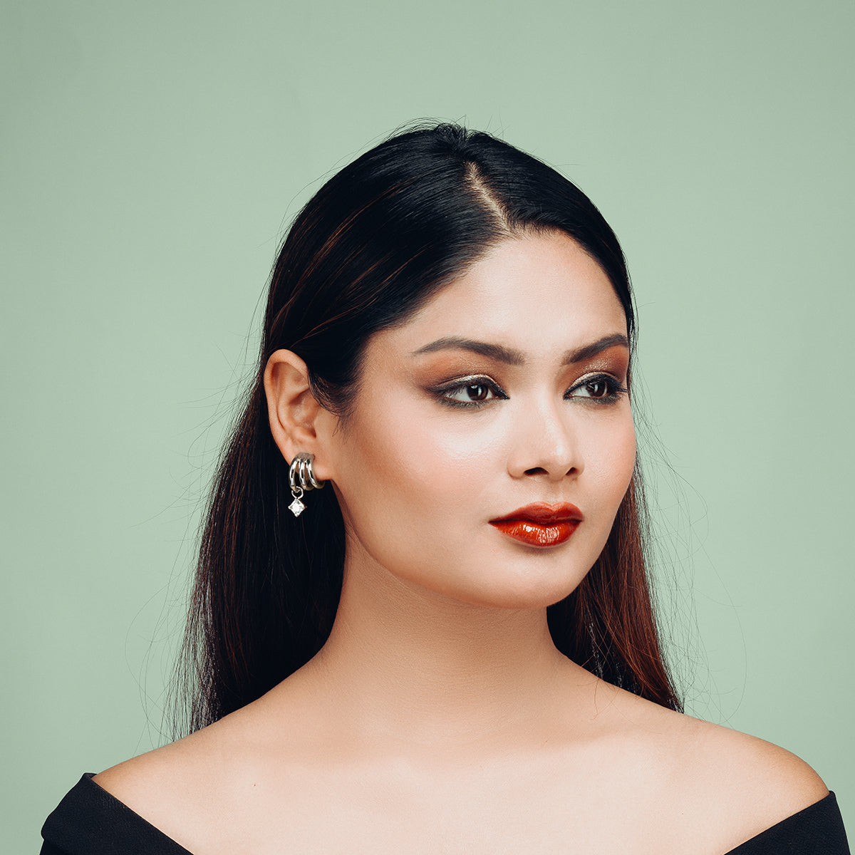 Portrait of a woman wearing Gulban’s Hyperbola Silver Hoop Earring in 18K gold plated finish. A modern dual hoop design with a solitaire charm, styled as premium demi fine jewellery for elegant wear.