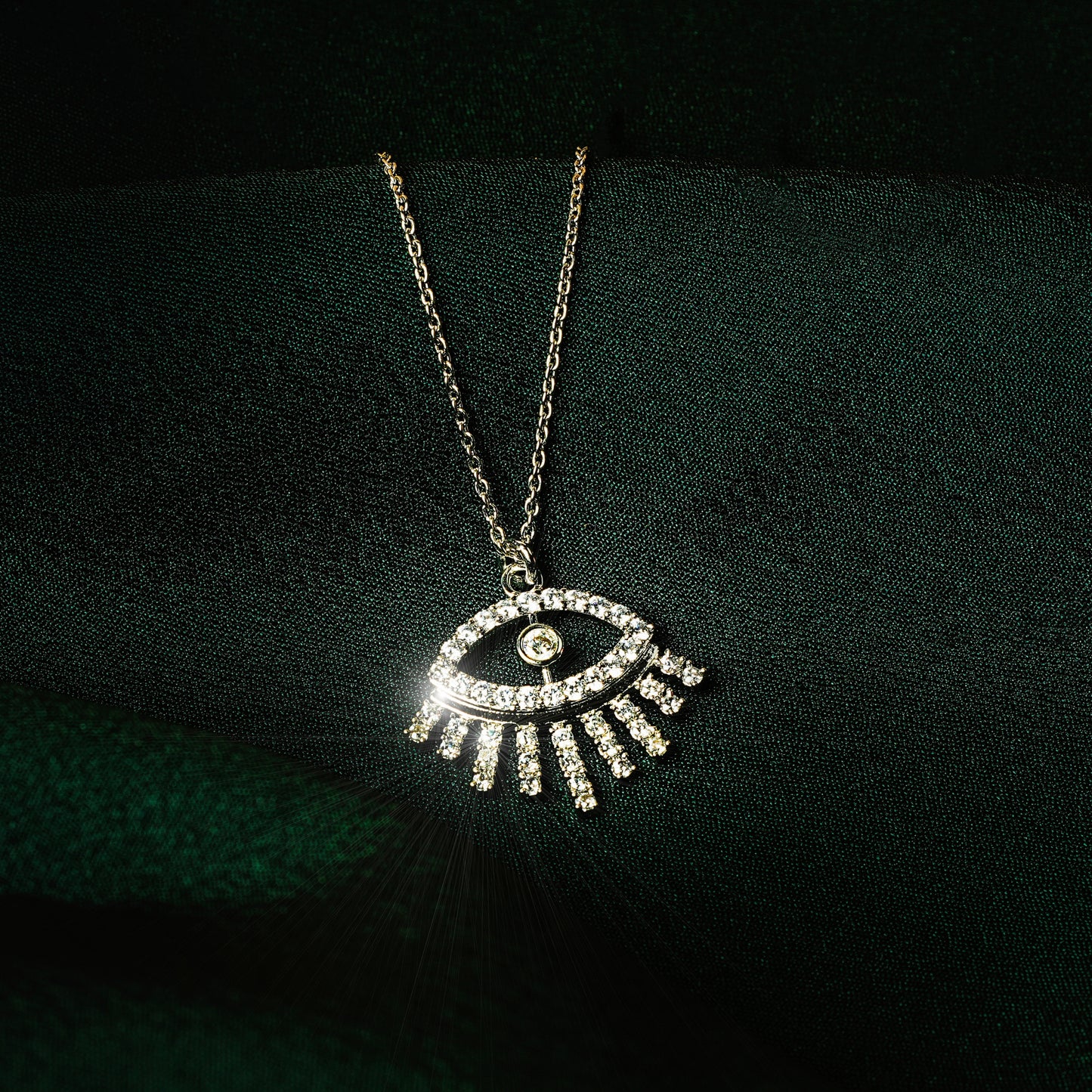 Silver eye pendant necklace for women with sparkling cubic zirconia stones in a minimalist modern design — demi-fine jewellery photographed on dark green satin