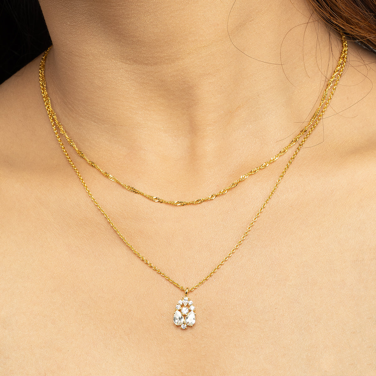 Close-up of Stellar Flow Pendant Set featuring a sparkling floral diamond cluster pendant paired with a delicate golden swirl chain, worn with an elegant off-shoulder black dress; a perfect blend of timeless sophistication and modern jewellery style for special occasions.