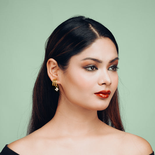 Model wearing Hyperbola Gold Hoop Earrings by Gulban, featuring demi fine jewellery style with 18K gold plating and a solitaire charm, perfect for chic everyday or festive looks.
