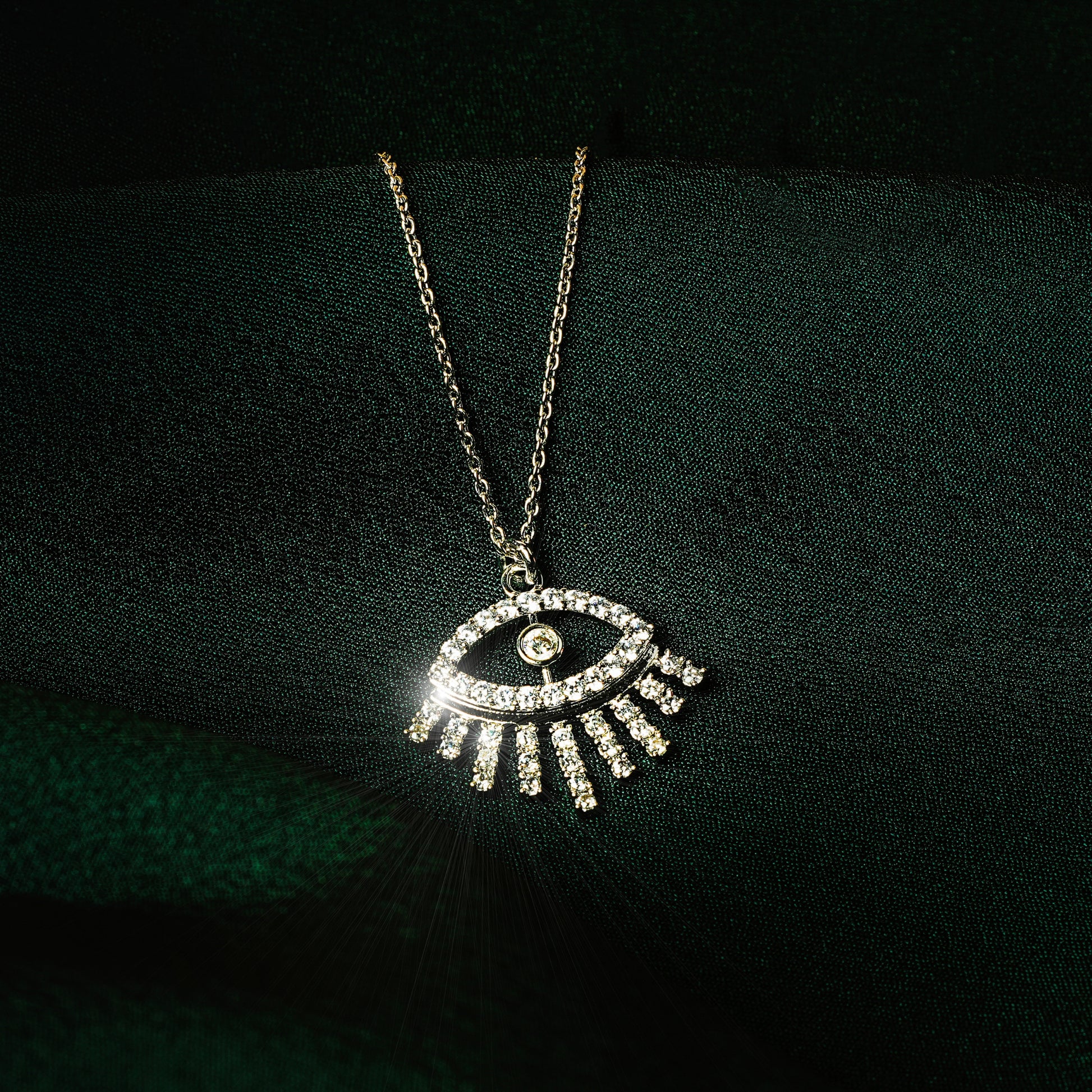 Silver eye pendant necklace for women with sparkling cubic zirconia stones in a minimalist modern design — demi-fine jewellery photographed on dark green satin