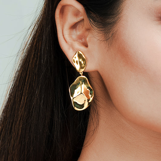 Close-up view of elegant Sense Drop Earring in gold tone, highlighting its fluid teardrop design and polished finish, worn by model to showcase Gulban’s luxury statement jewellery craftsmanship against a soft pastel background.